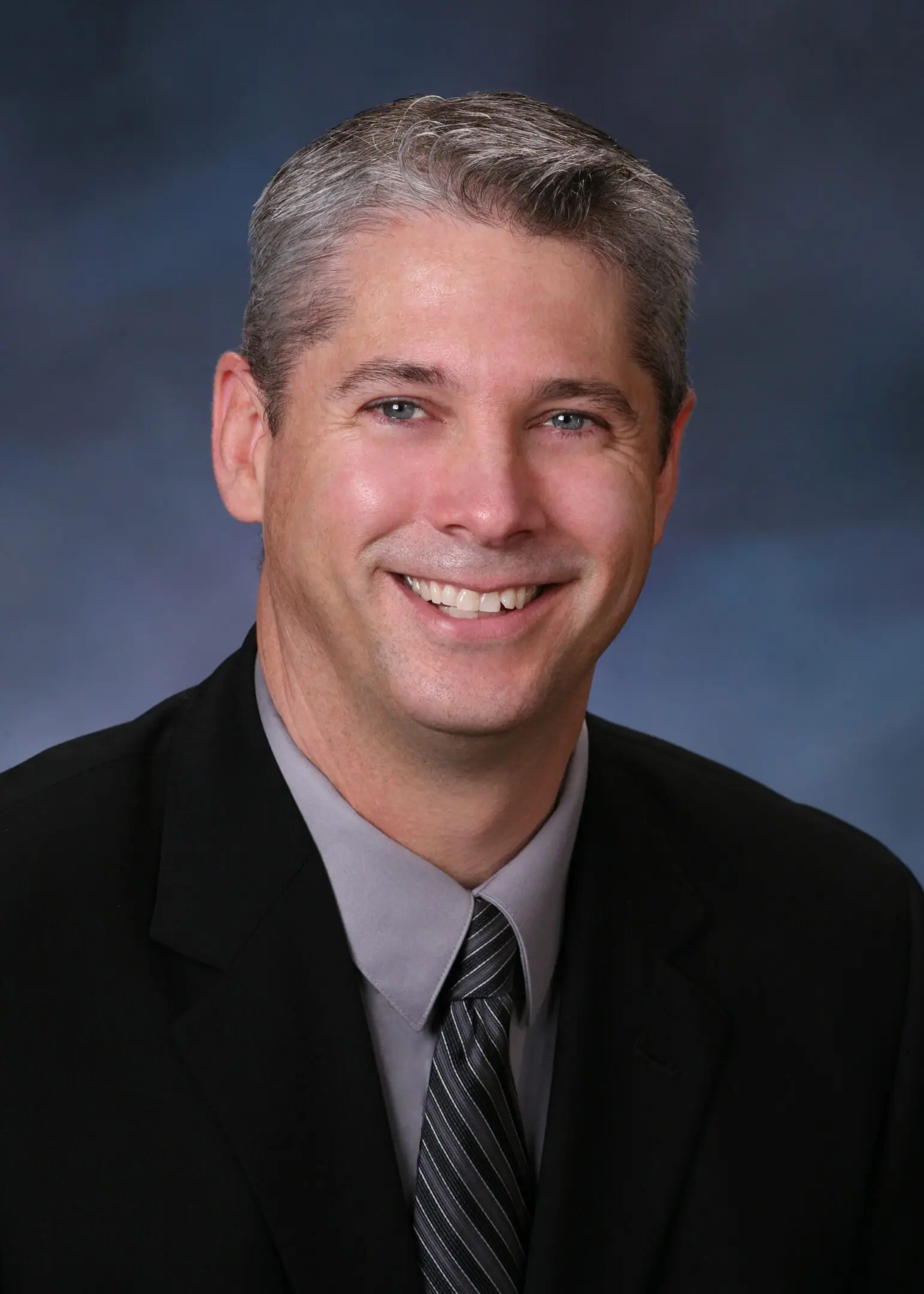 A man in suit and tie smiling for the camera.